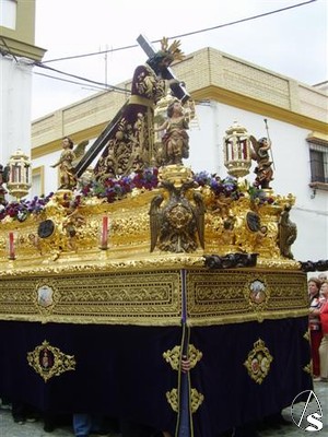  Procesiona sobre un paso de estilo neobarroco, lleva respiraderos bordados en oro sobre terciopelo morado con cartelas de seda y malla inspirados en los del Señor de Sevilla