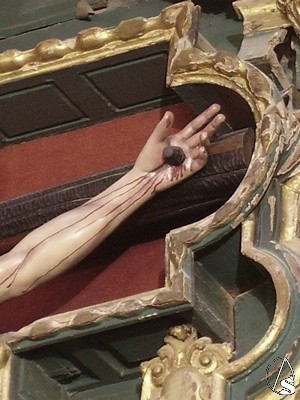 Detalle de la mano izquierda del crucificado en la que observa caer por el brazo la sangre de la herida producida por el clavo