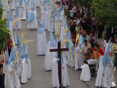 Los nazarenos, niños en su mayoría visten túnica y capa blanca con antifaz celeste 